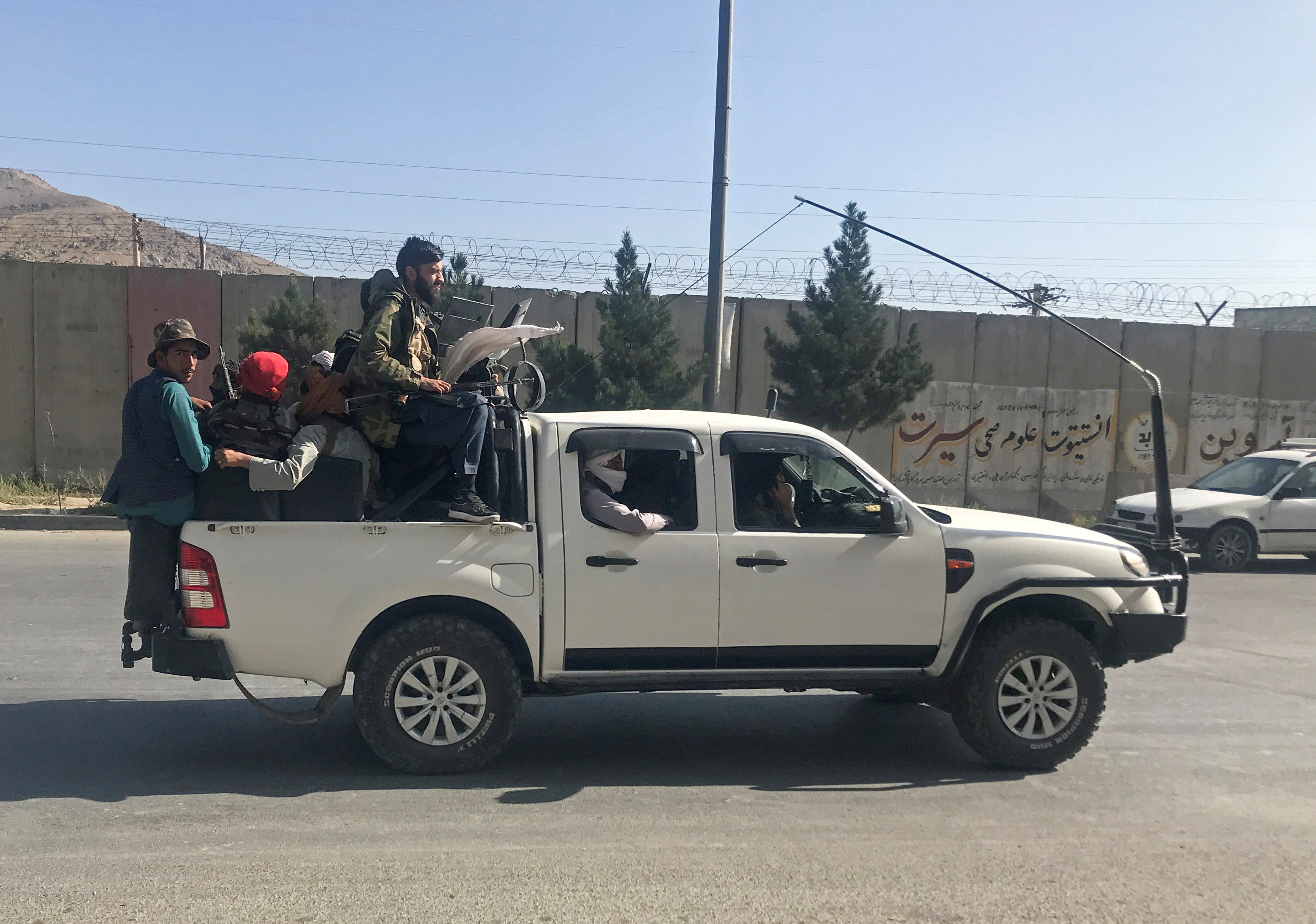 Taliban fighters ride on a vehicle in Kabul