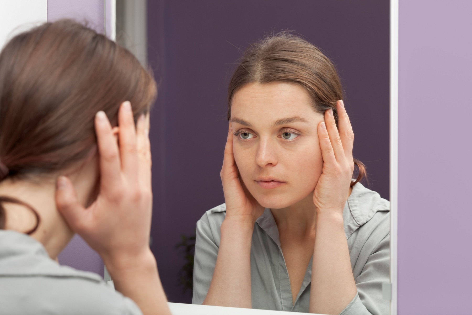 Woman checking ageing skin at the mirror