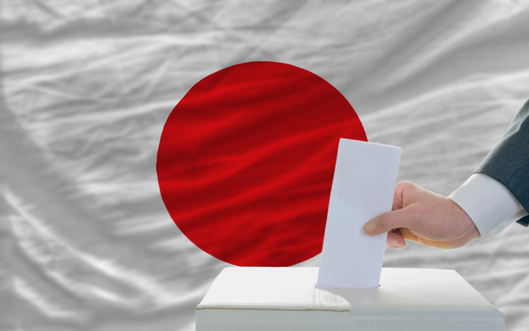 man voting on elections in japan in front of flag