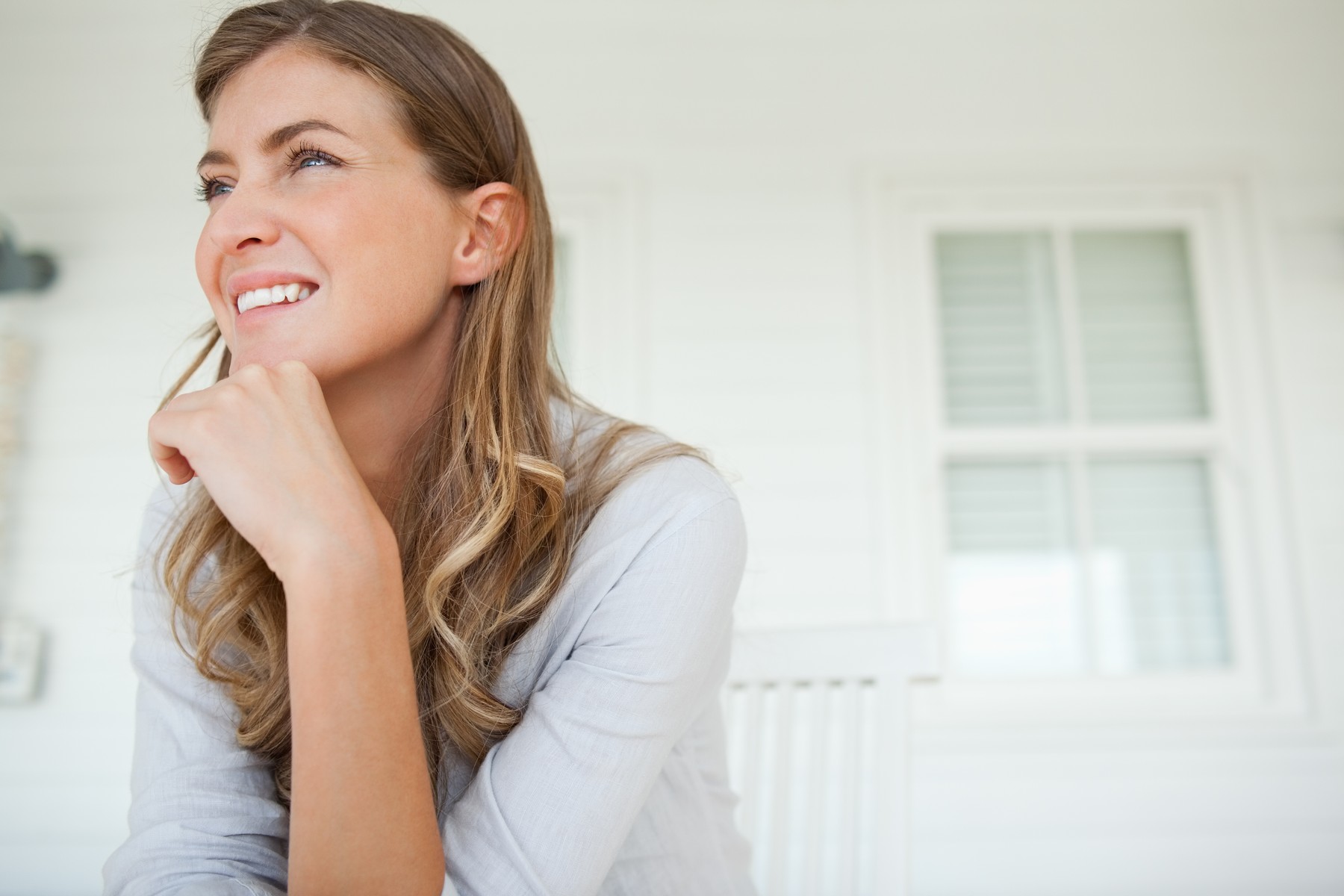 Woman with a hand on her chin looks slightly up