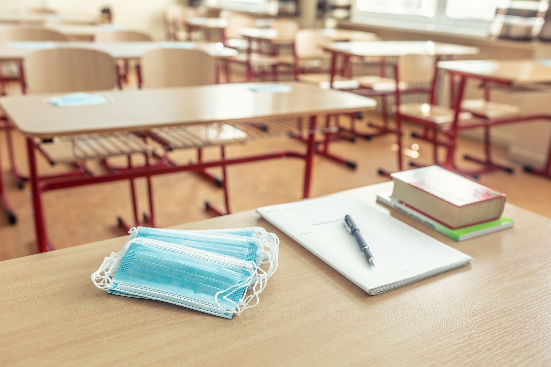 Face mask on a teachers and school desk in a school classroom.
