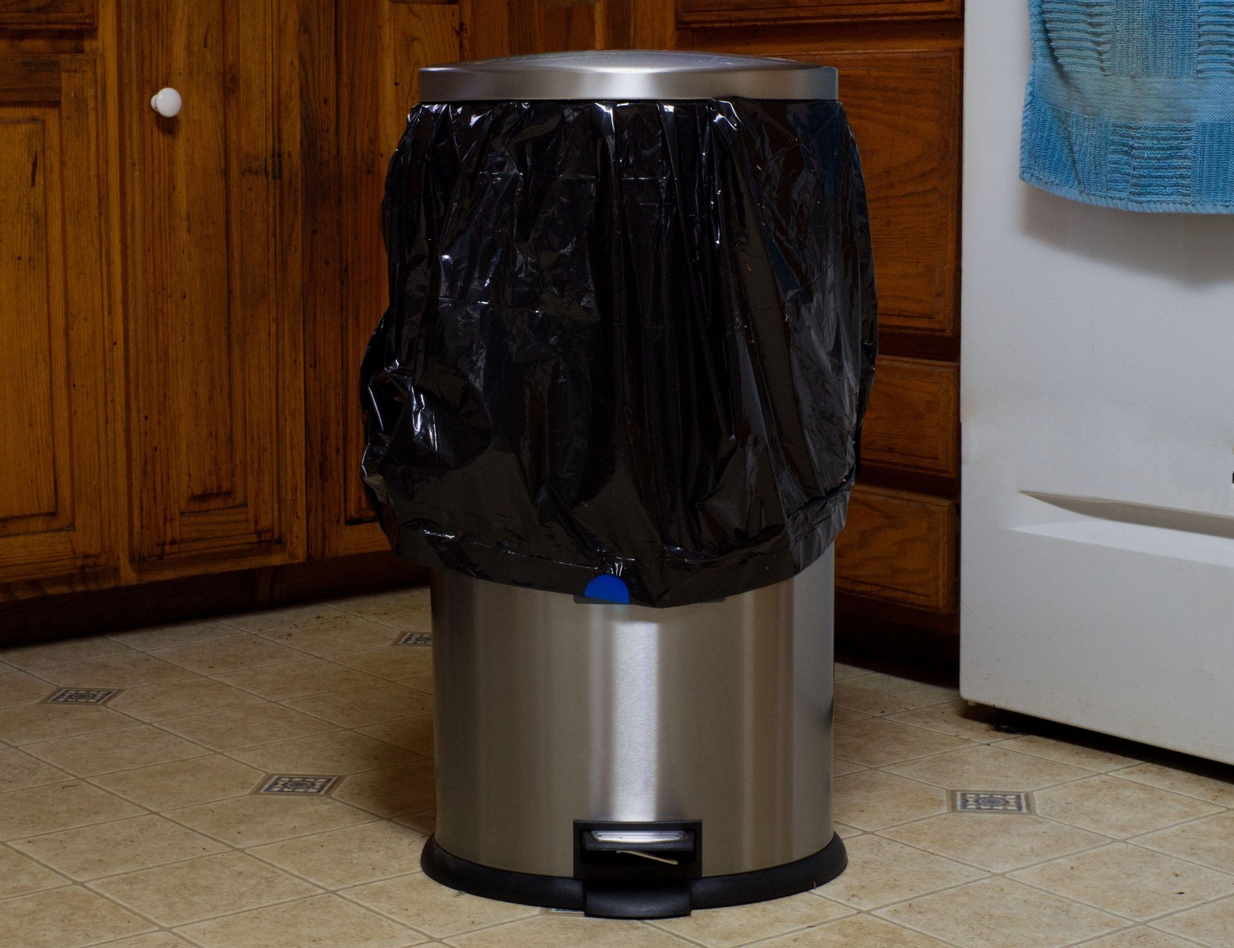 A Stainless Steel Garbage Can With a Black Plastic Trash Bag