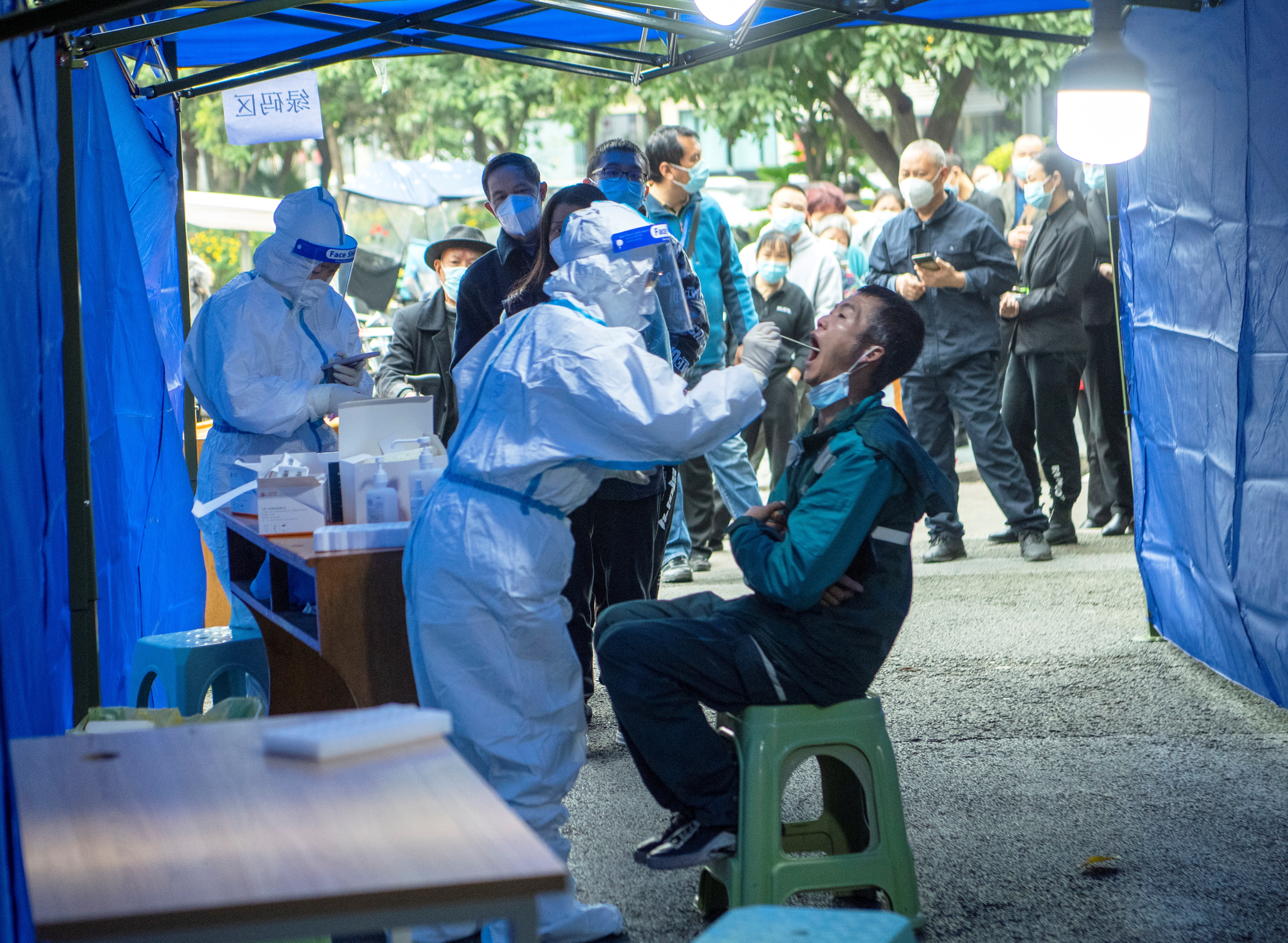 People line up at a nucleic acid testing site near a residential compound under lockdown in Chengdu