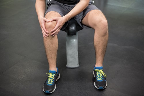 Man with an injured knee sitting in gym