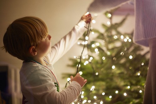 Young boy putting up christmas tree lights