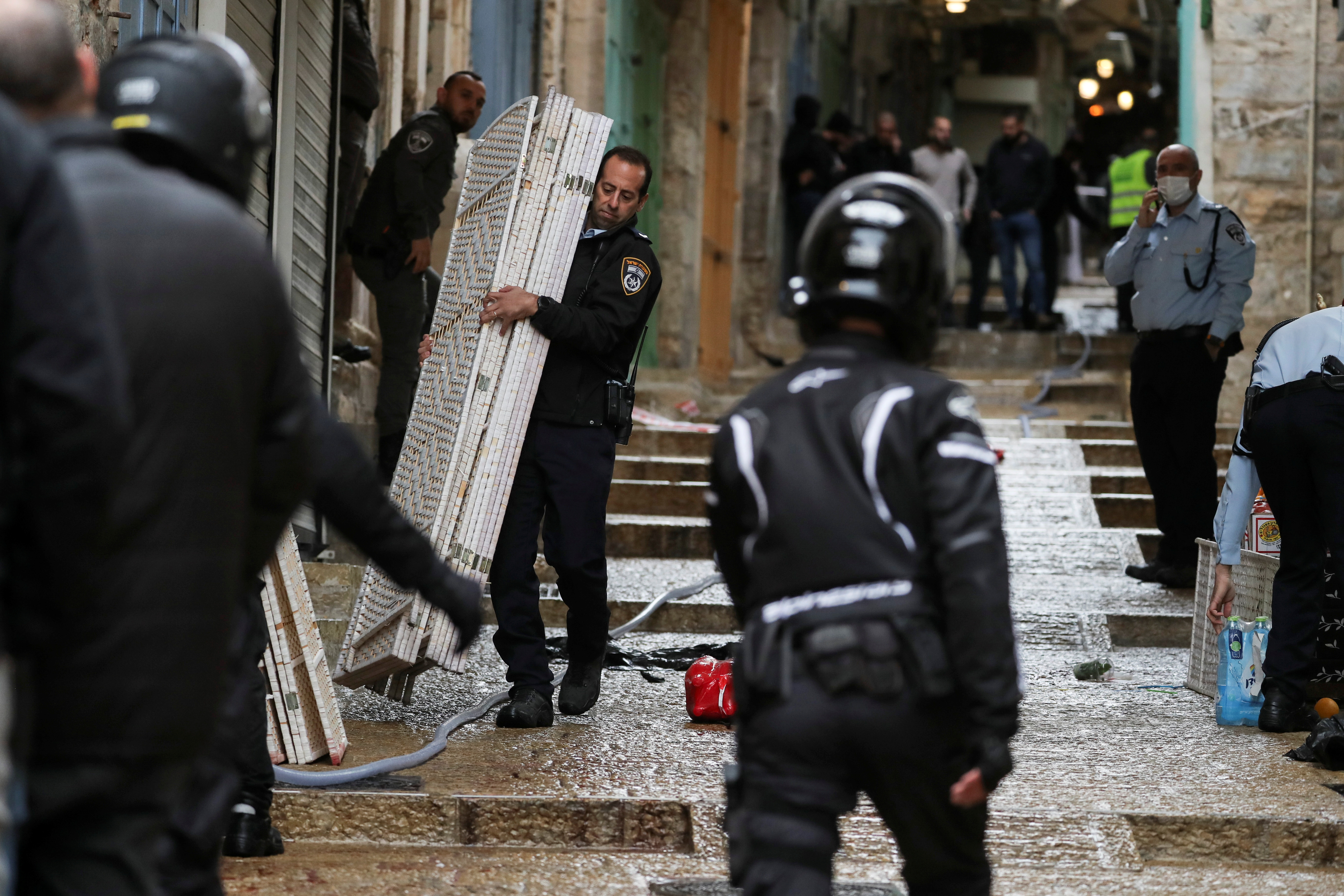 An Israeli policeman carries a privacy partition near the site of a shooting incident in Jerusalem's Old City