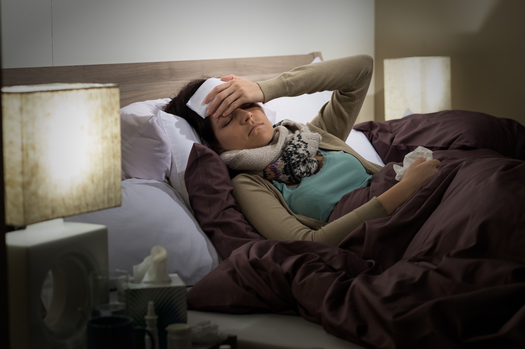 Young woman lying sick in bed cold