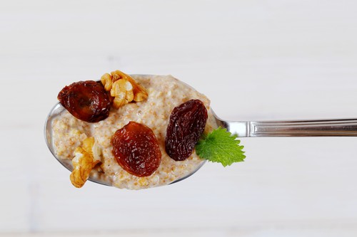spoon of oatmeal porridge with raisins and walnuts