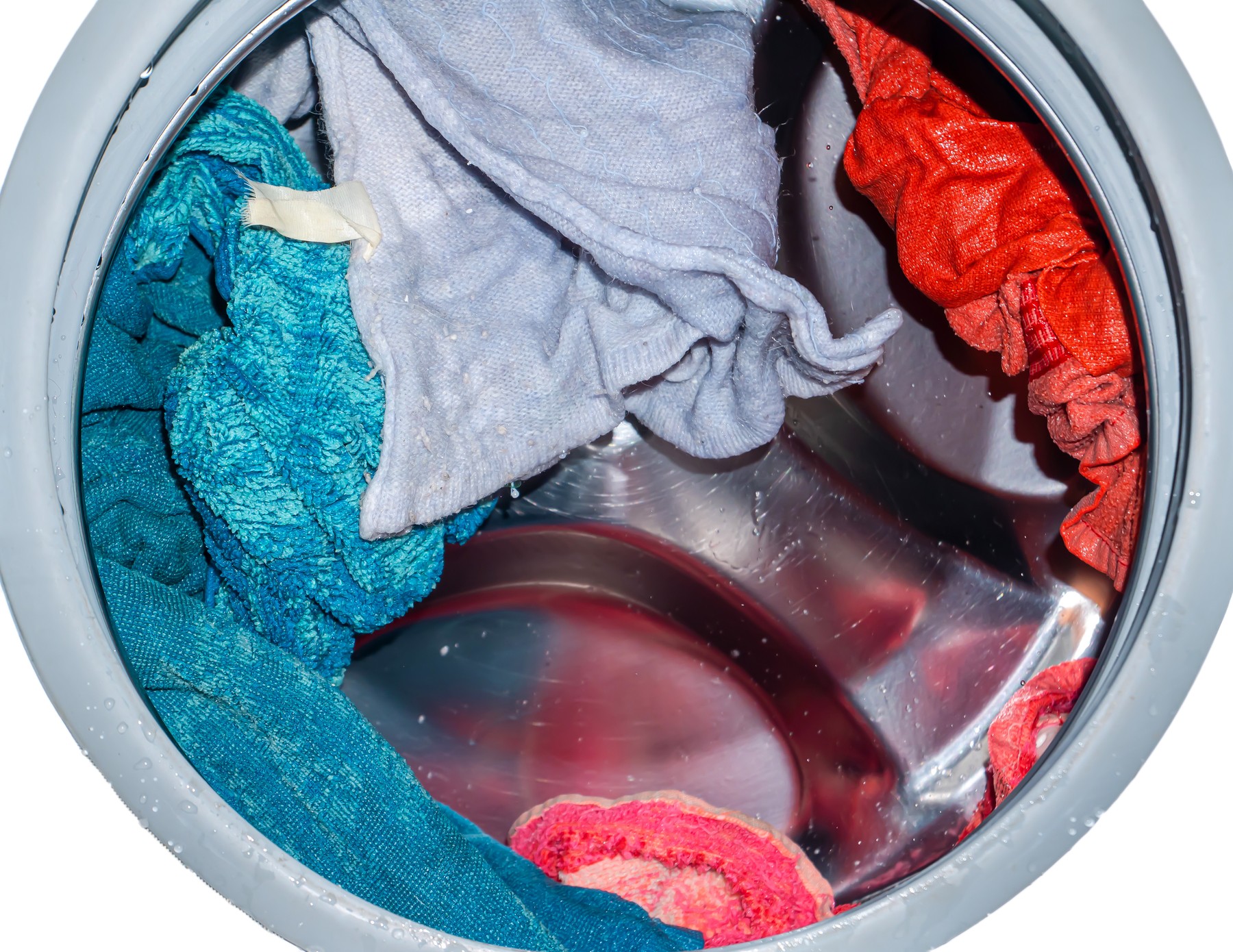 Rotating drum in a washing machine tub with clothes.