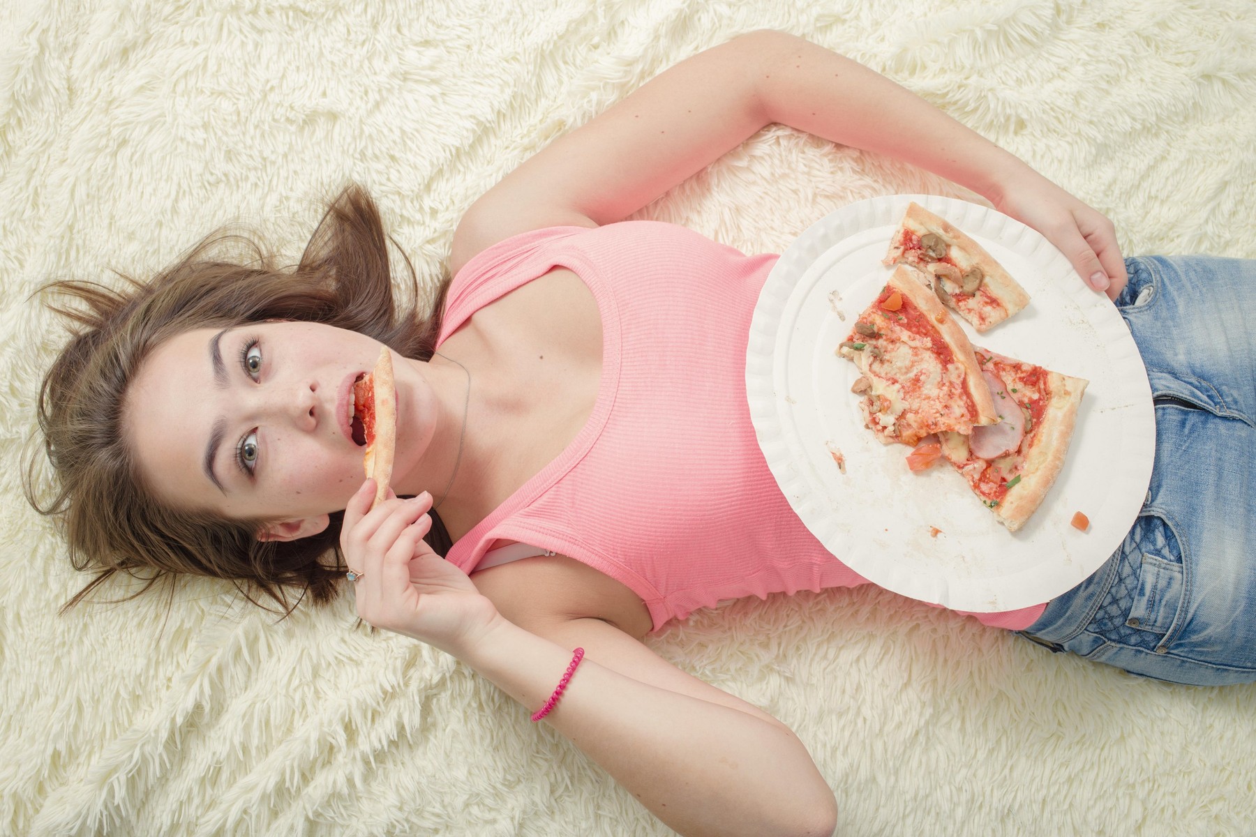 sad overeat girl lying with pizza pieces
