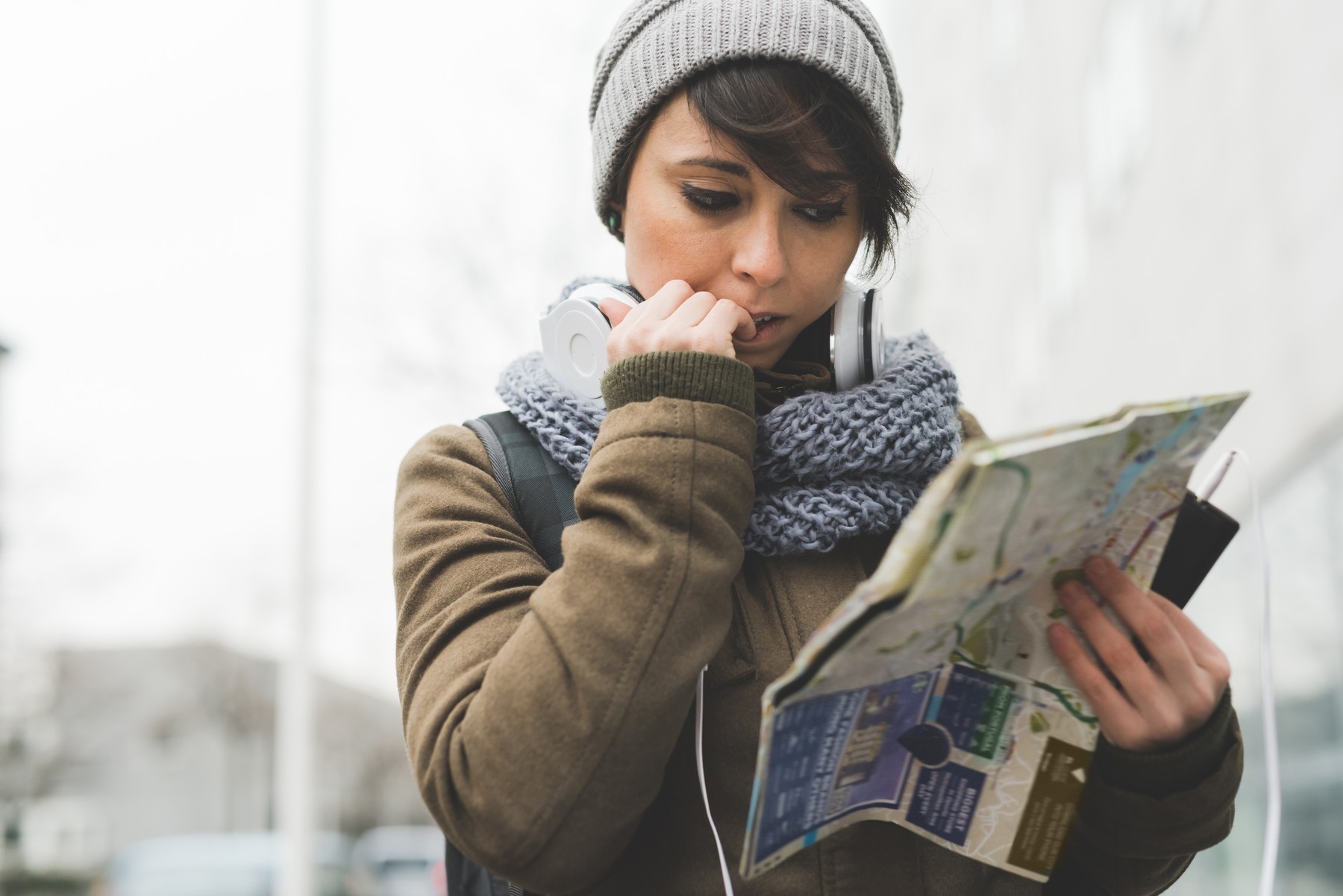 Female backpacker biting nails and looking at map in city