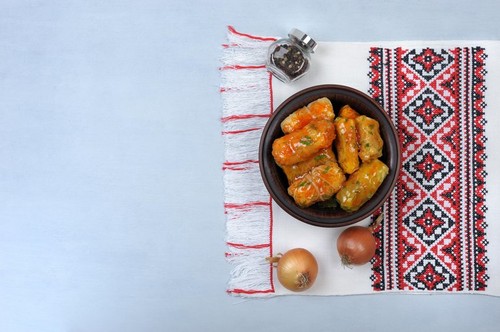 Stuffed cabbage leaves  with  rice and meat in tomato sauce on an embroidered towel on a gray background.