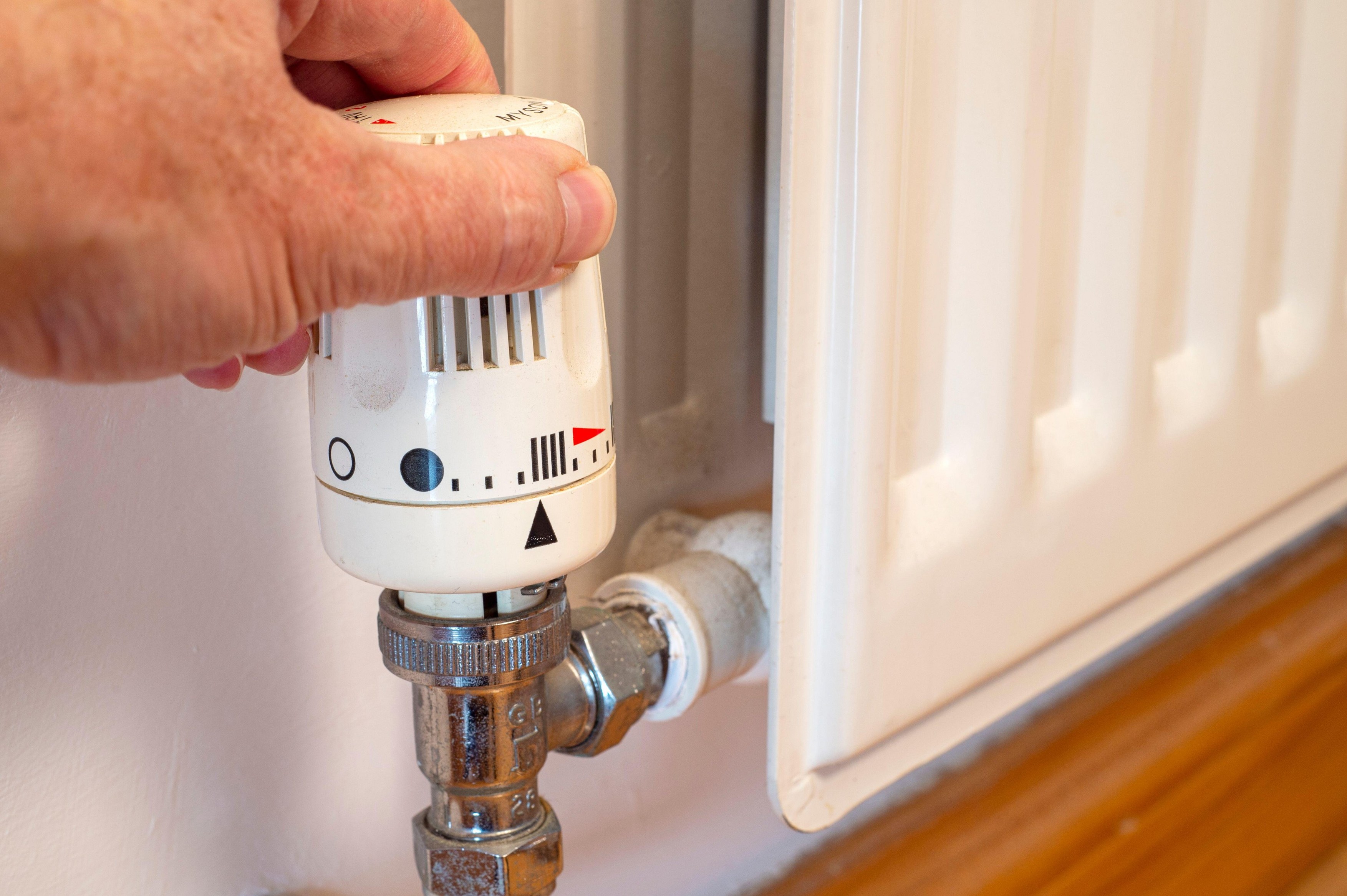 Man's hand adjusting the temperature of a radiator