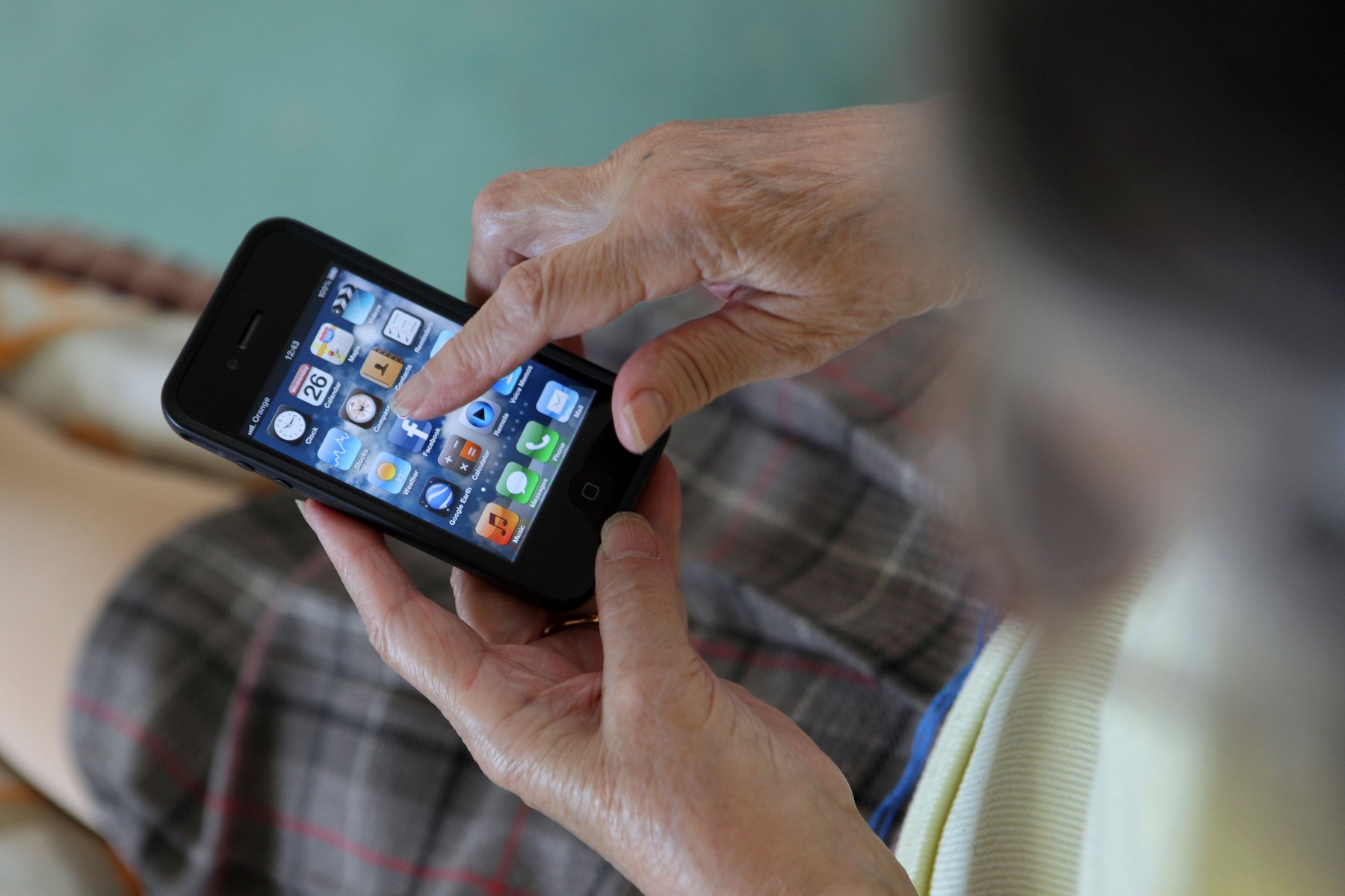 Getting to grips with smartphone 3G technology, an elderly old woman uses her iPhone to browse Facebook