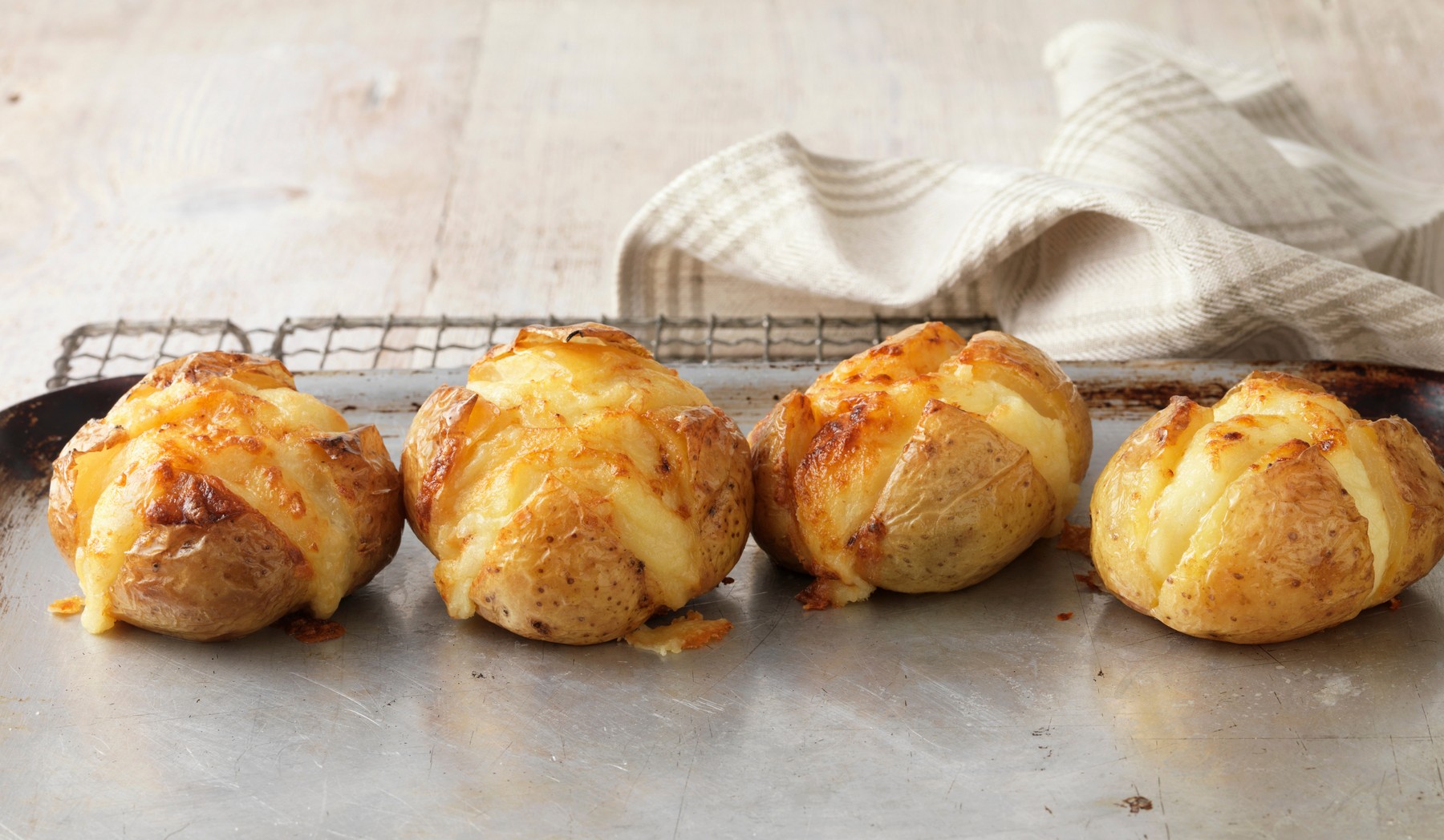 Jacket potatoes baked in oven with cheese on metal baking tray