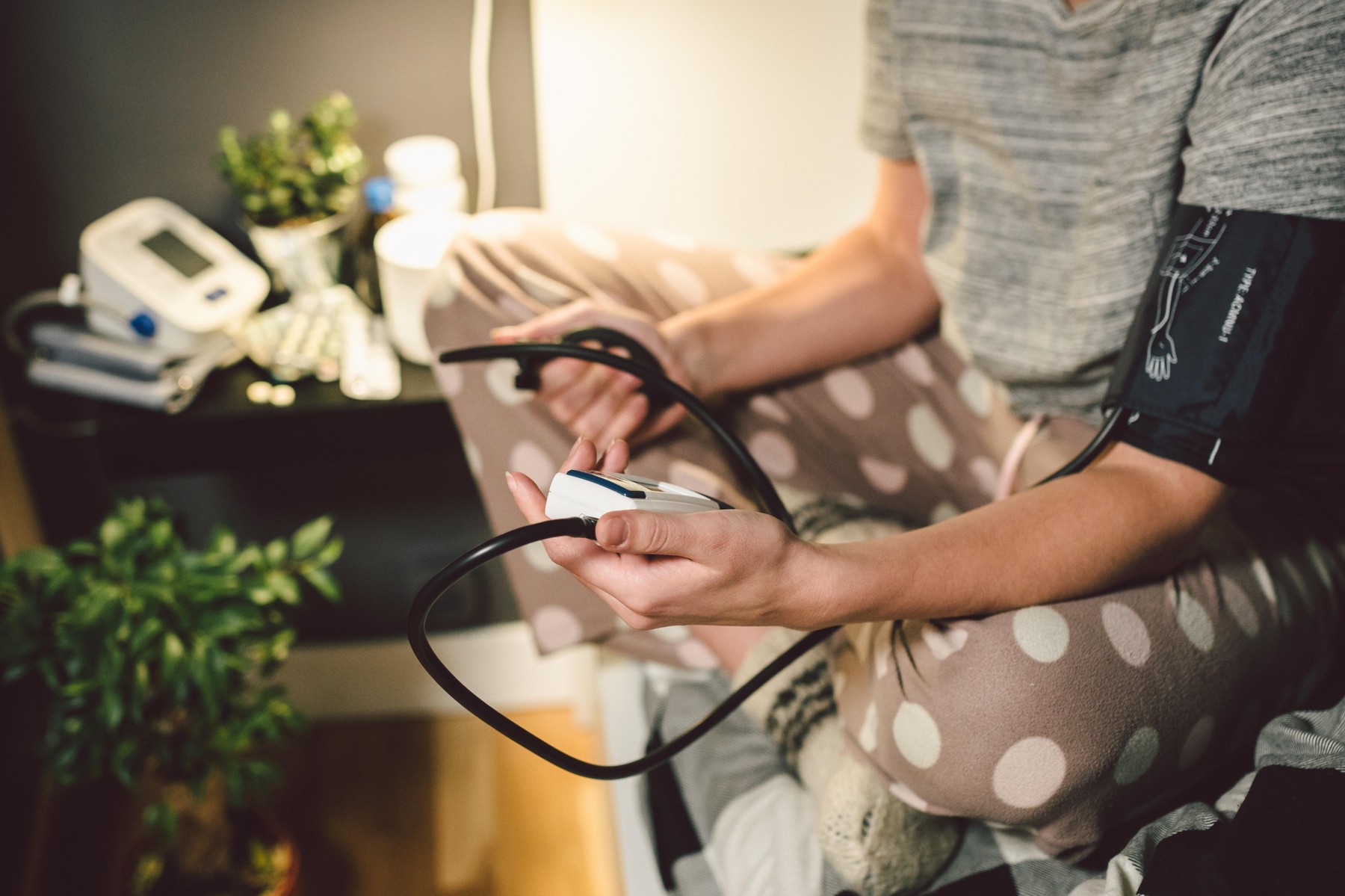The topic of high blood pressure is hypertension disease. Close-up macro young caucasian woman hands using automatic tonometer to check pressure at ho