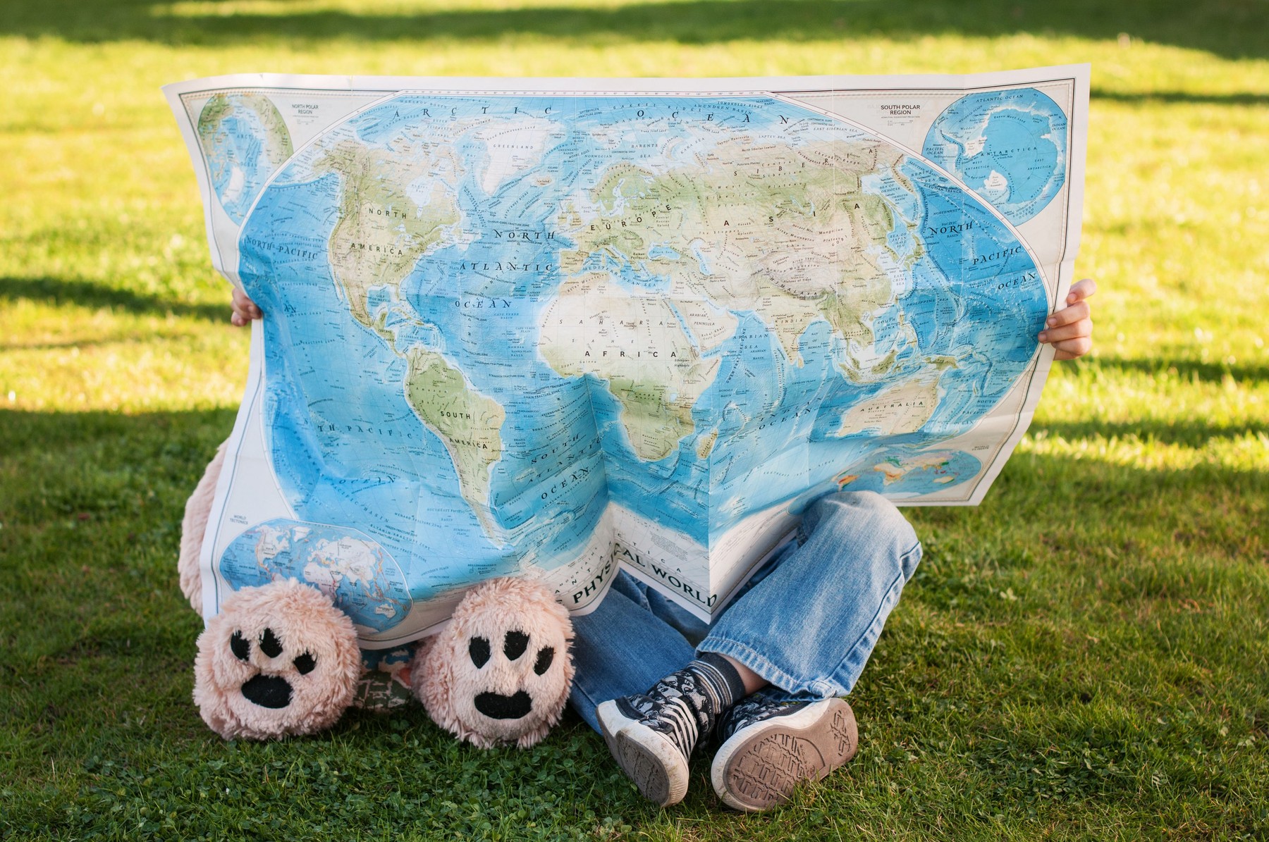 Child and Teddy bear looking at world map