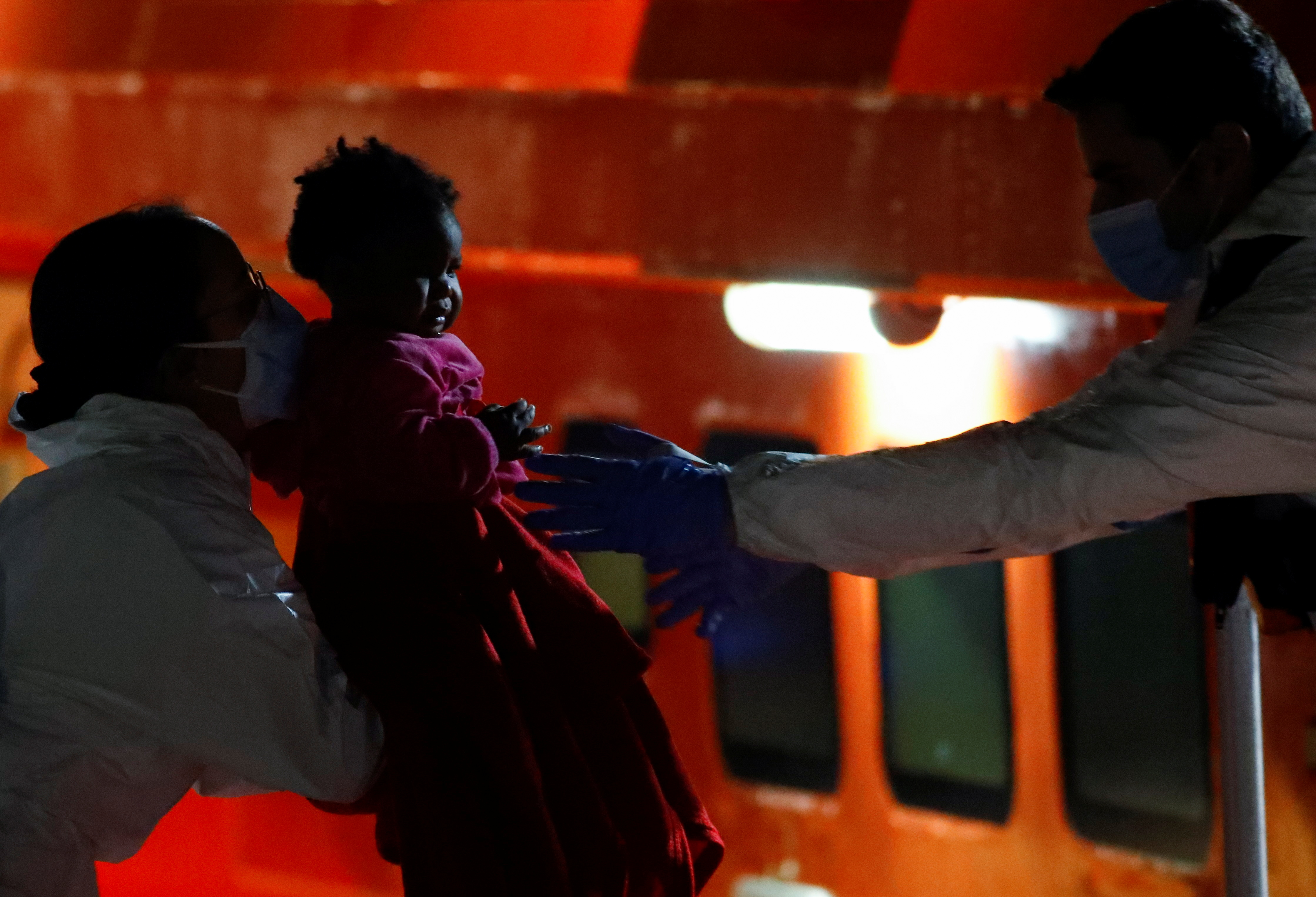 A rescuer disembarks a migrant minor from a Spanish coast guard vessel, at the port of Arguineguin