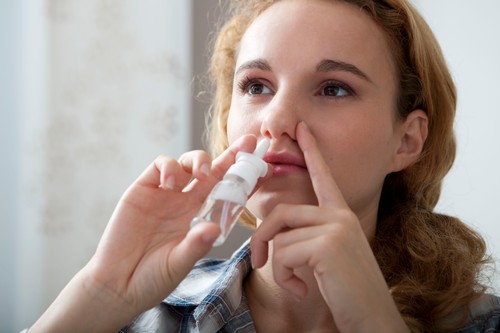 WOMAN USING NOSE SPRAY