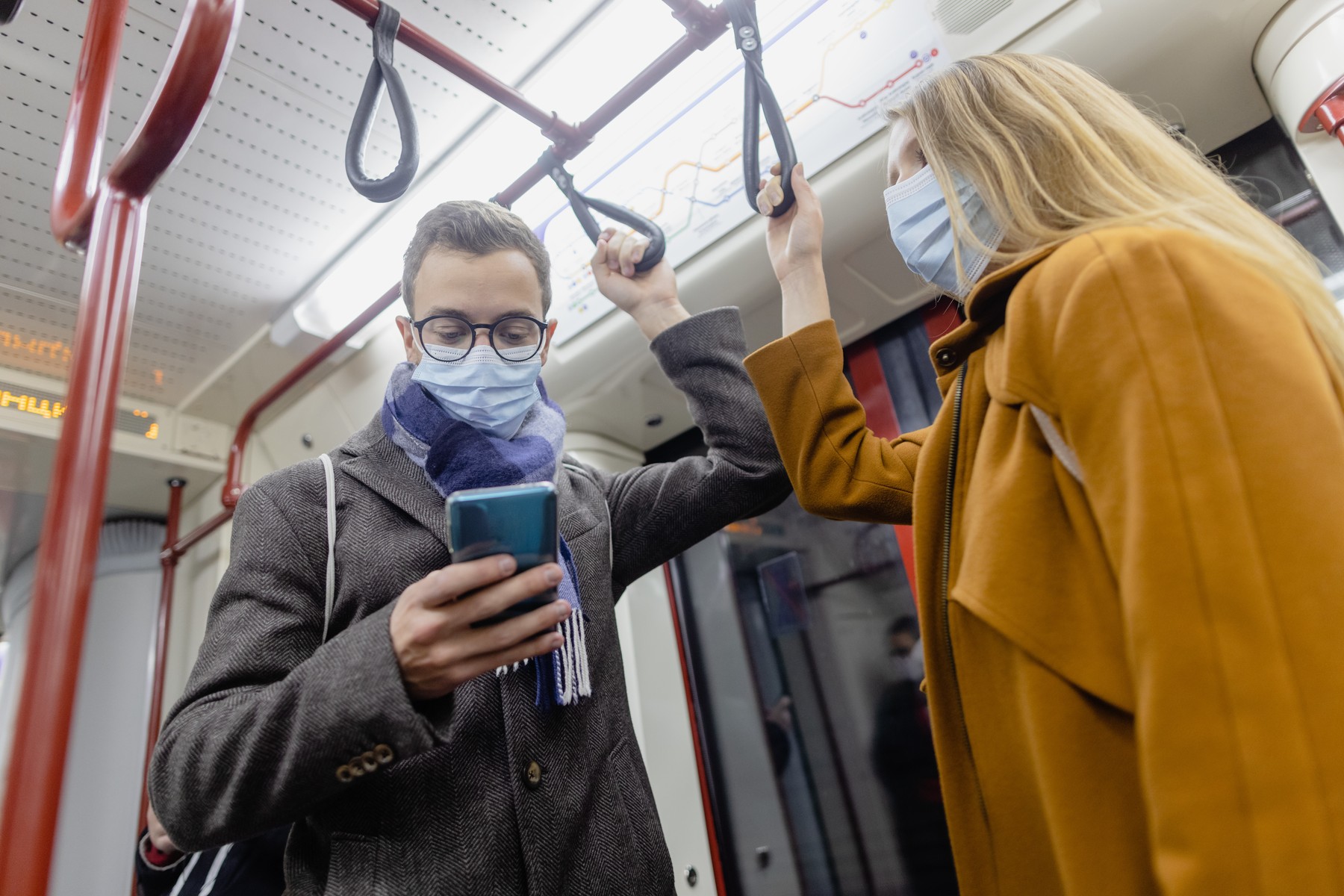 People using phone in train wearing covid-19 face mask