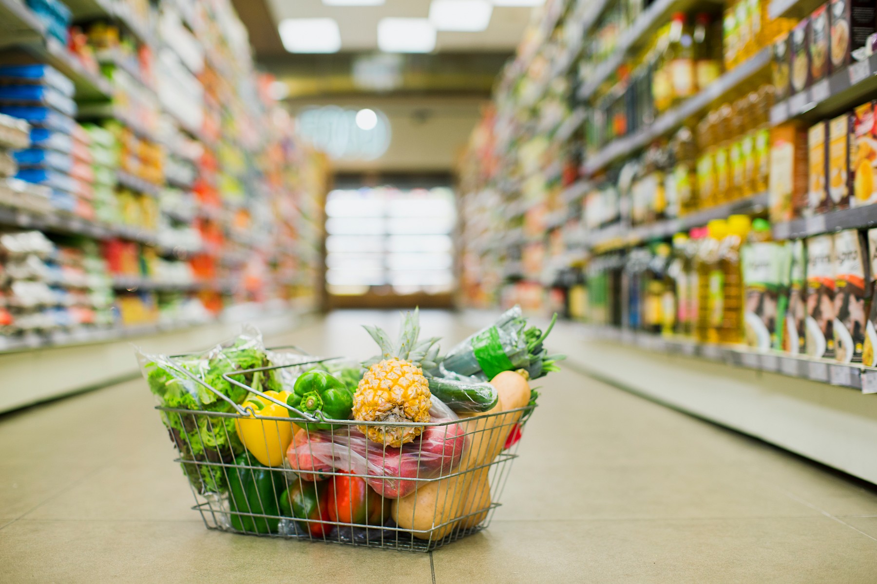Close up of full shopping basket on floor of grocery store