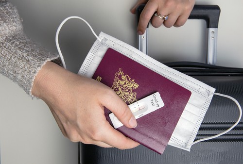 COVID-19, travel and lockdown concept, Young womans hand with passport,medical mask and negative rapid test coronavirus and suitcase, Travel,requirement,health,covid and holiday concept