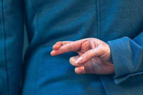 Fingers crossed behind back