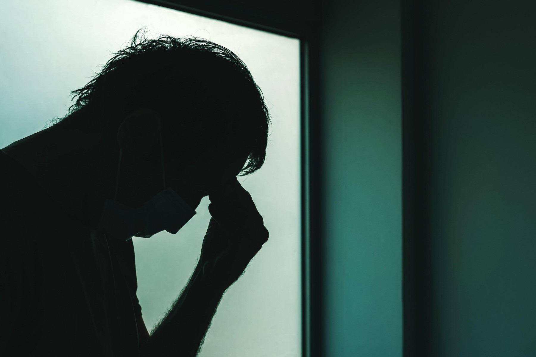 Covid-19 headache as infection symptom, man with respiratory mask holding a hand at his forehead