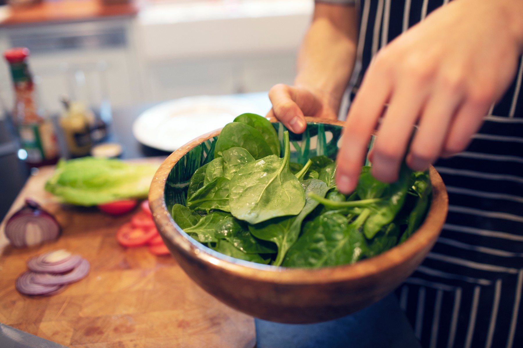 Close up teenage boy making spinach salad at home