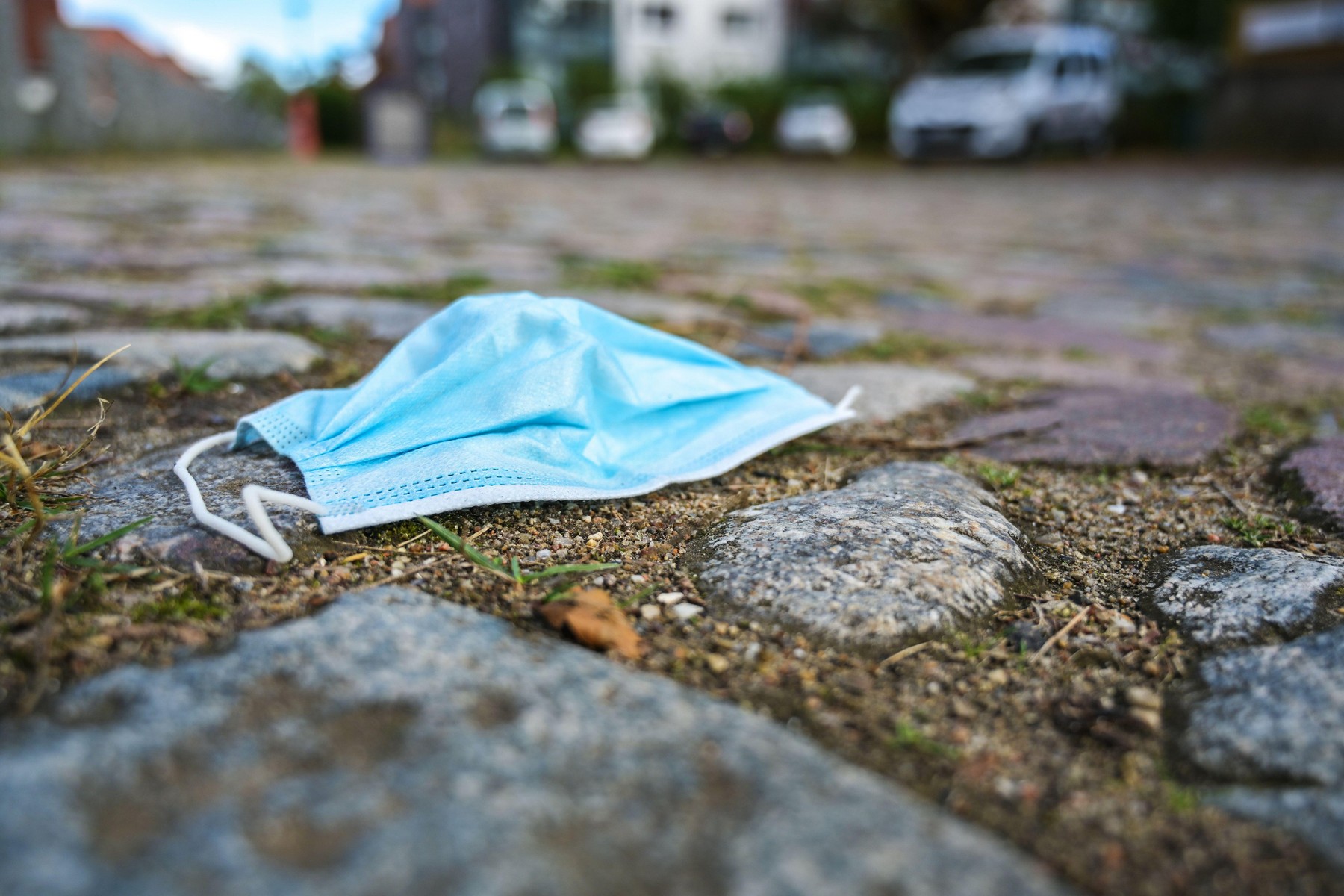 Surgical face mask against infection with coronavirus and covid-19 thrown away on a cobblestone square in the city, copy space, selected focus, very n