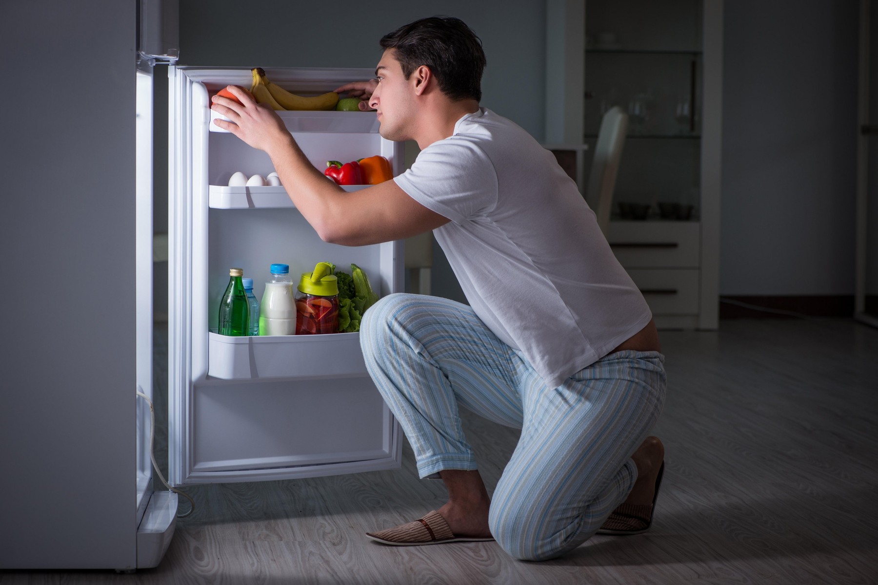 Man at the fridge eating at night