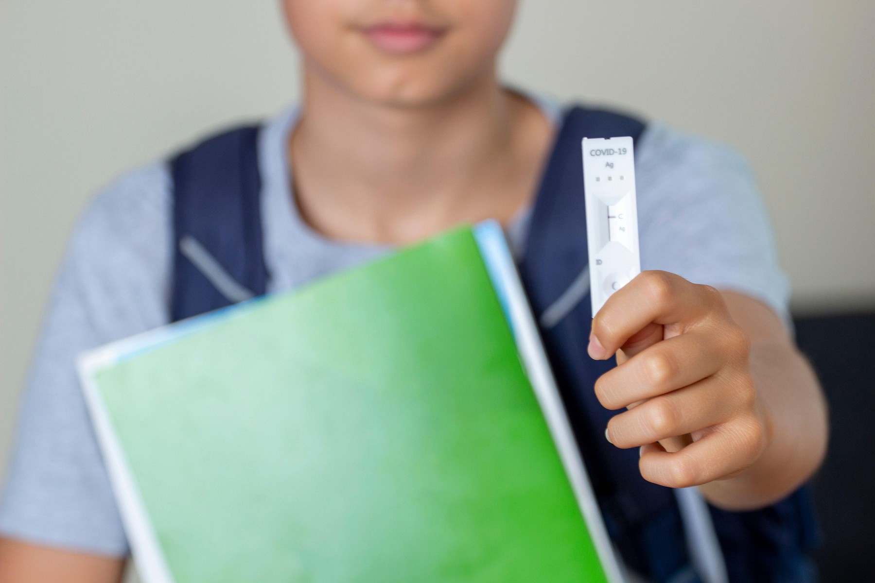 Teenage boy with backpack holding in hand rapid Coronavirus Covid-19 negative test device and show negative test result