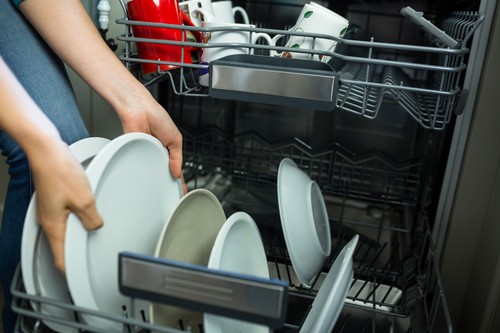 Pretty blonde woman emptying the dishwasher