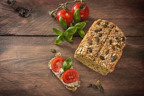 Homemade protein bread with tomatoes, basil and cream cheese on a dark rustic wooden table, healthy slimming with low carb or ketogenic diet, copy spa