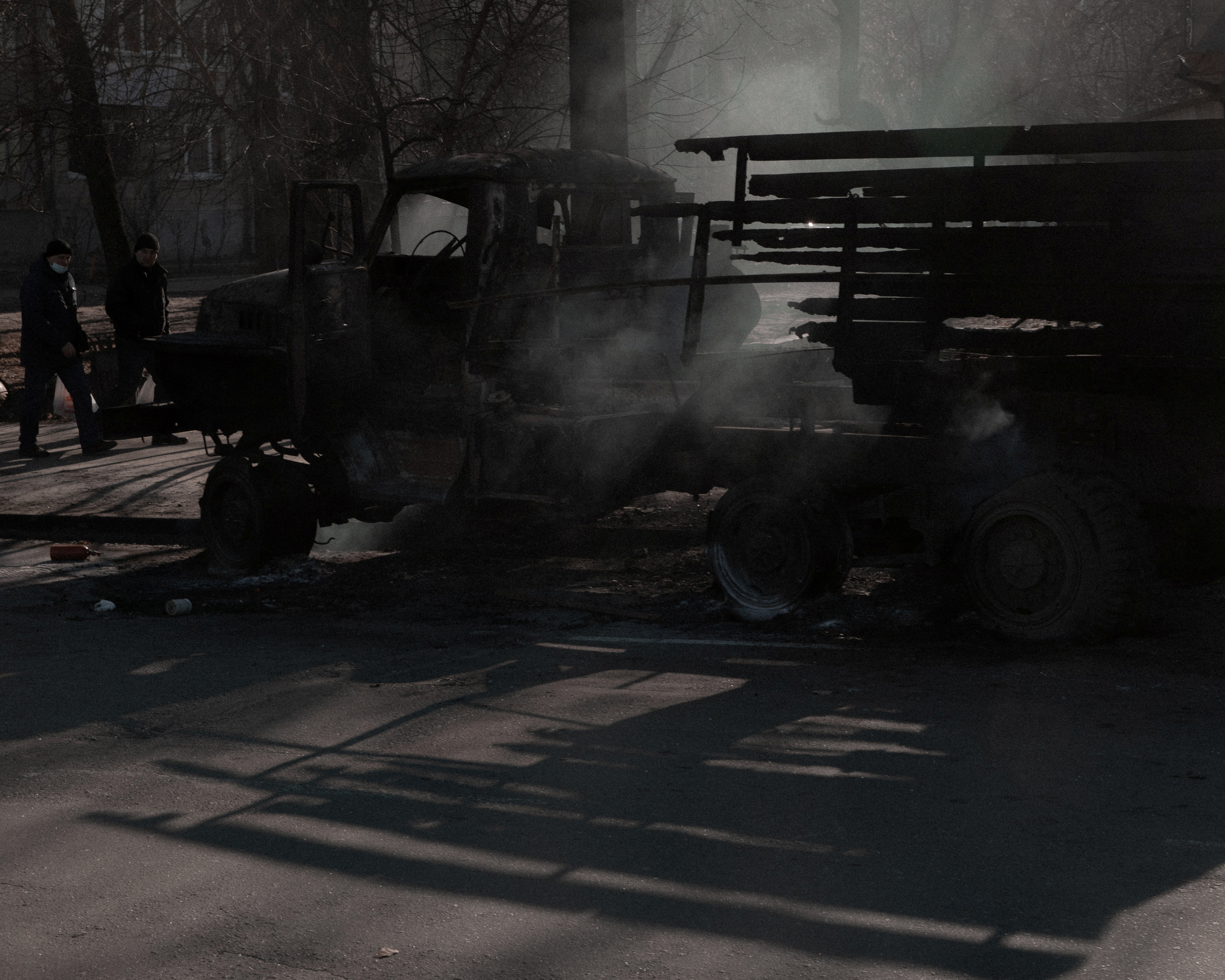 People walk past a burnt vehicle in Kyiv