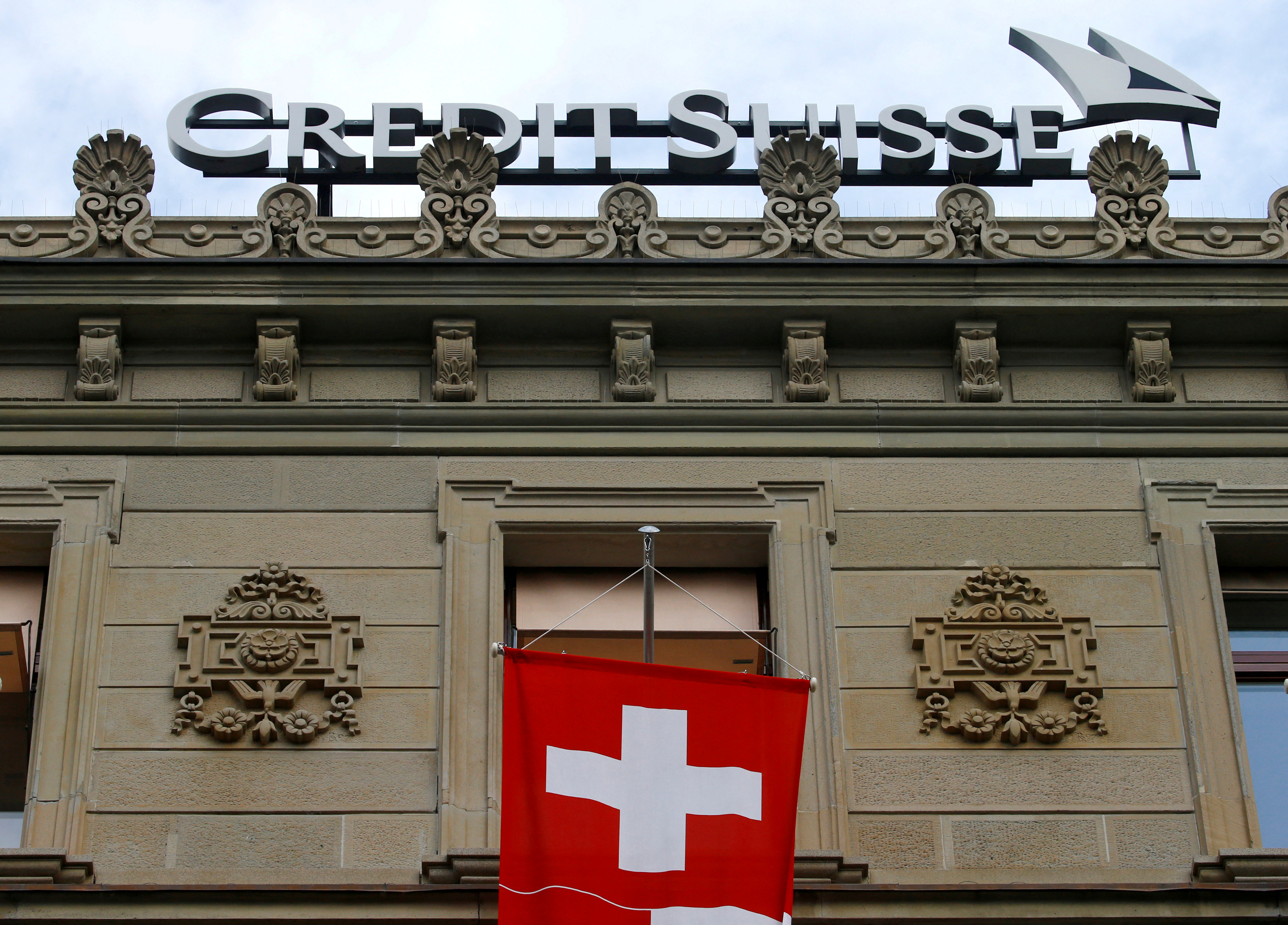 FILE PHOTO: Switzerland's national flag flies below a logo of Swiss bank Credit Suisse in Zurich