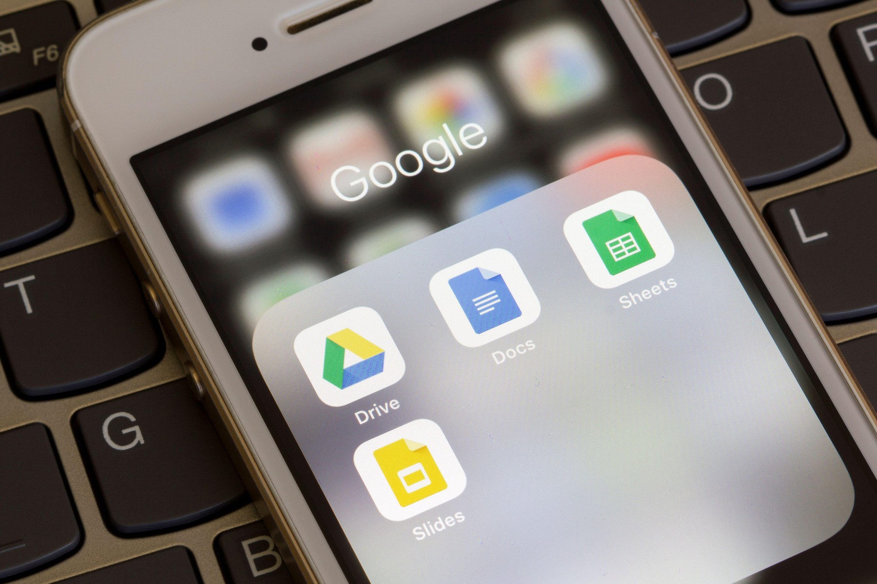Mobile app icons of Google Drive Enterprise suite with Google Docs, Sheets, and Slides are seen on a smartphone.