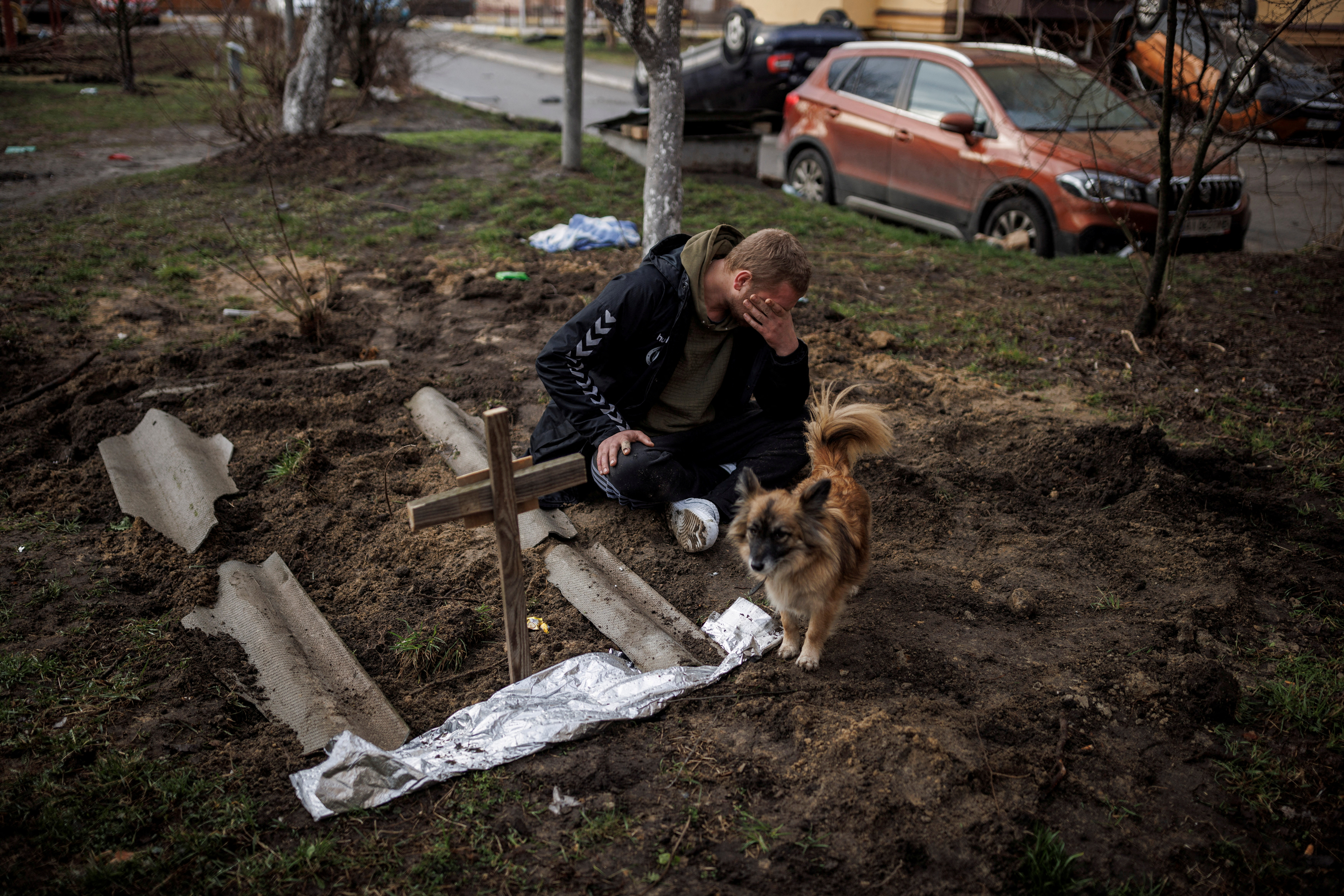 Serhii Lahovskyi mourns next to the grave of his friend Ihor Lytvynenko, in Bucha