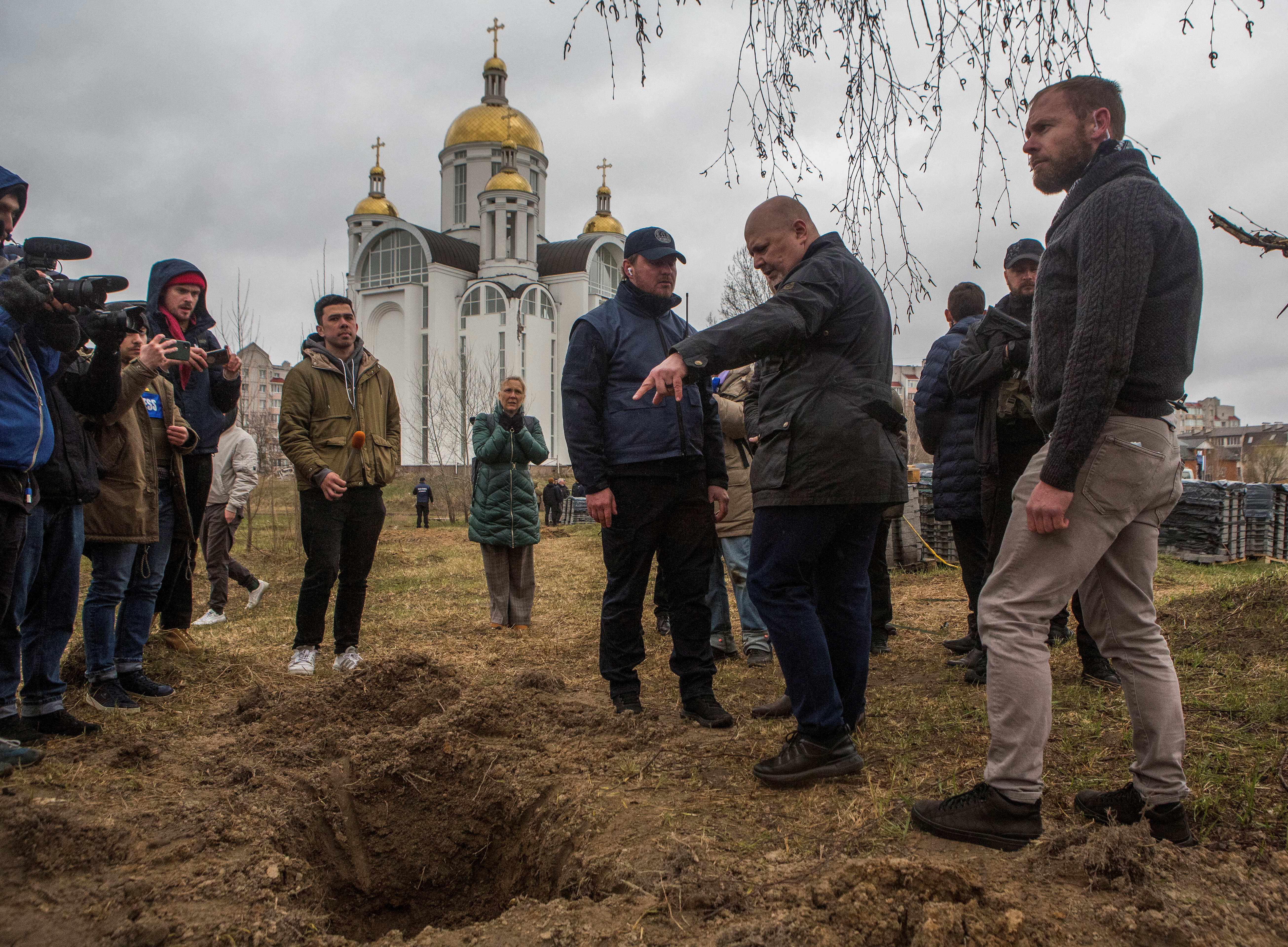 International Criminal Court Prosecutor Khan stands next to a grave where remains of three bodies were found, in the town of Bucha