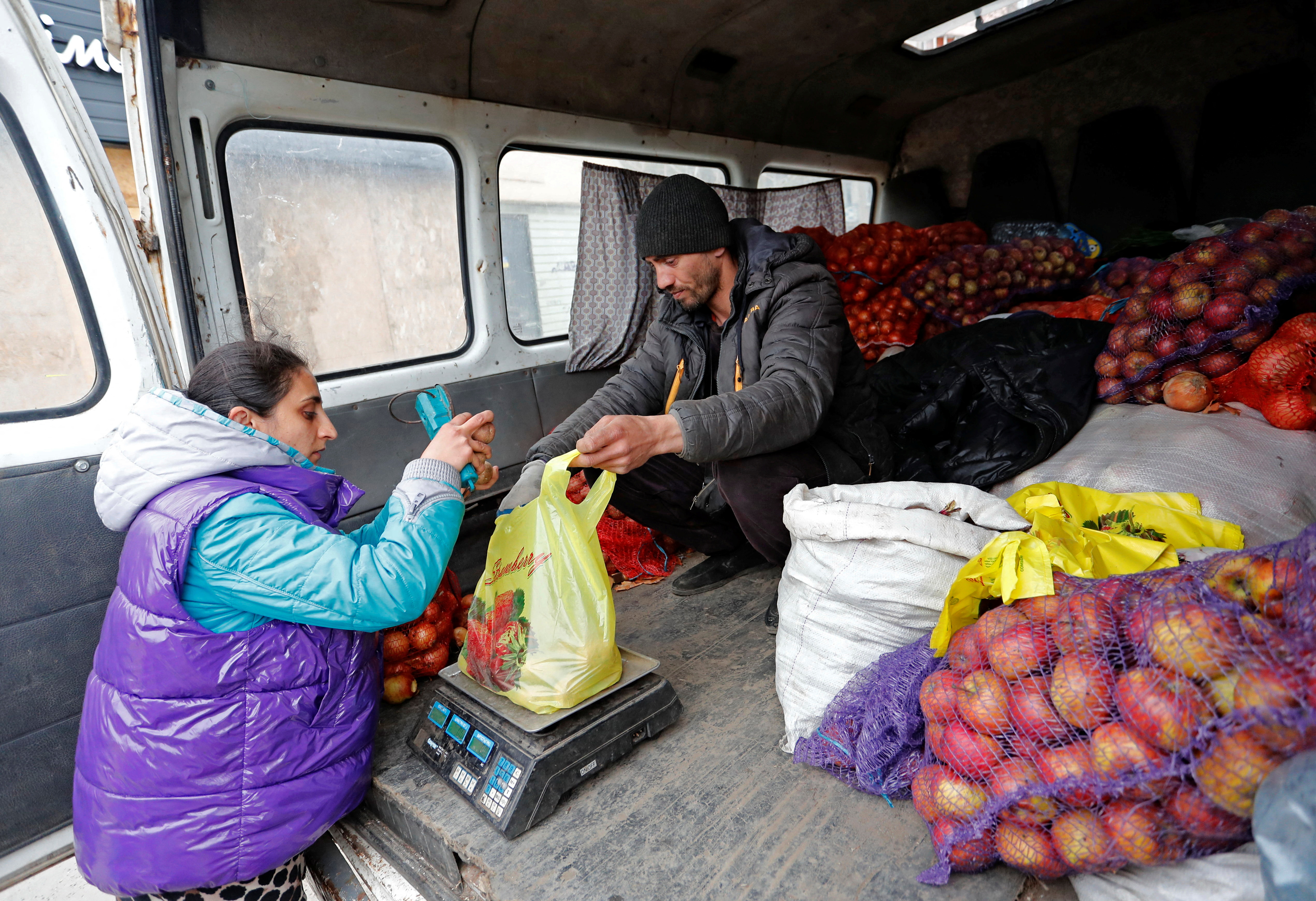 Vendors weigh potatoes at a local market in Mariupol