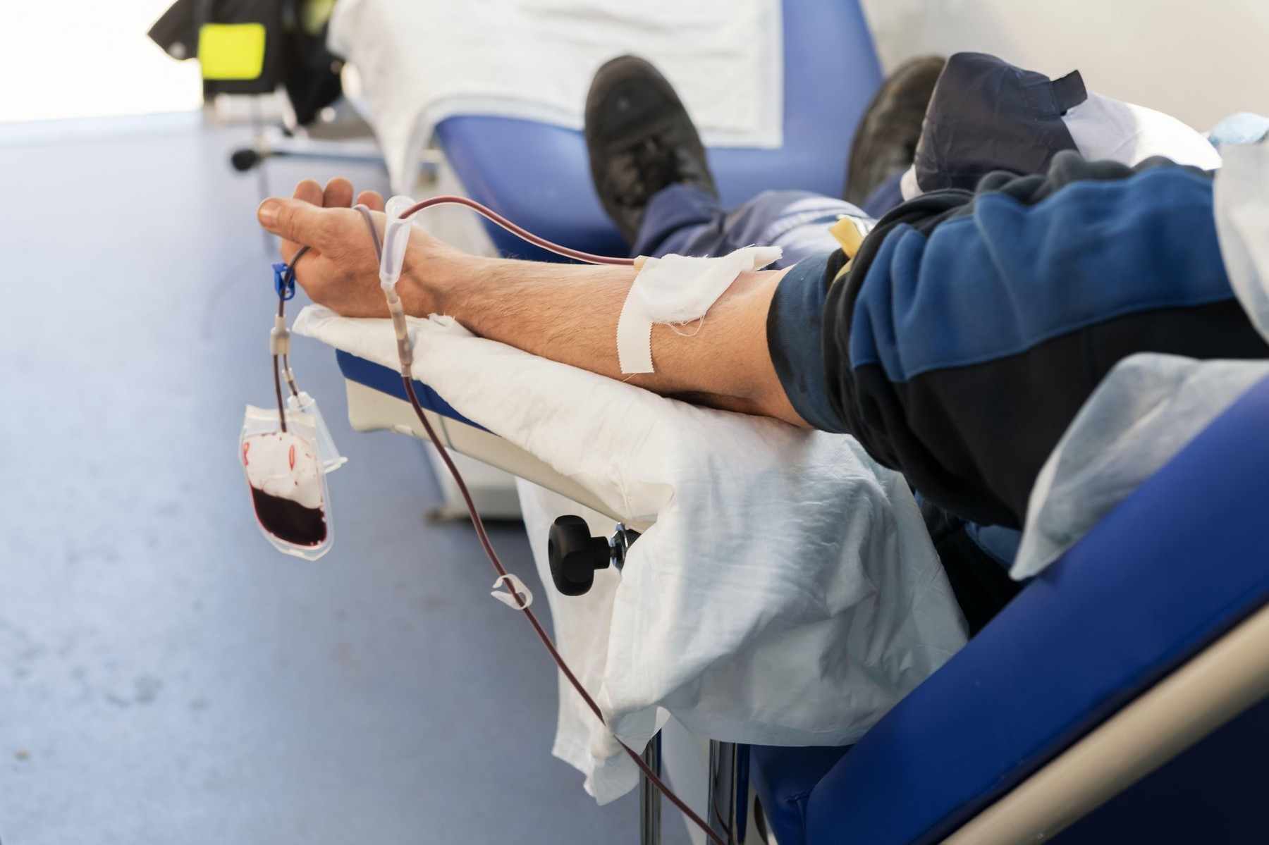 A hand of donor sitting on an armchair in a mobile blood bank during of blood collection. Donation to support the hospitals during coronavirus