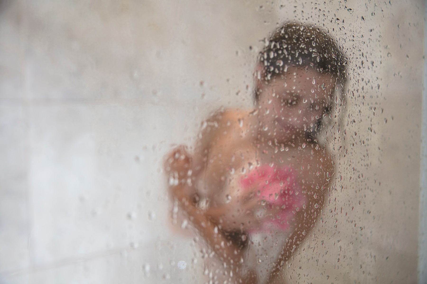 Young woman in shower behind glass door