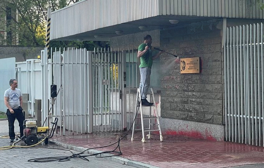 An employee cleans the entrance of the Polish embassy after the building was splattered with red paint in Moscow