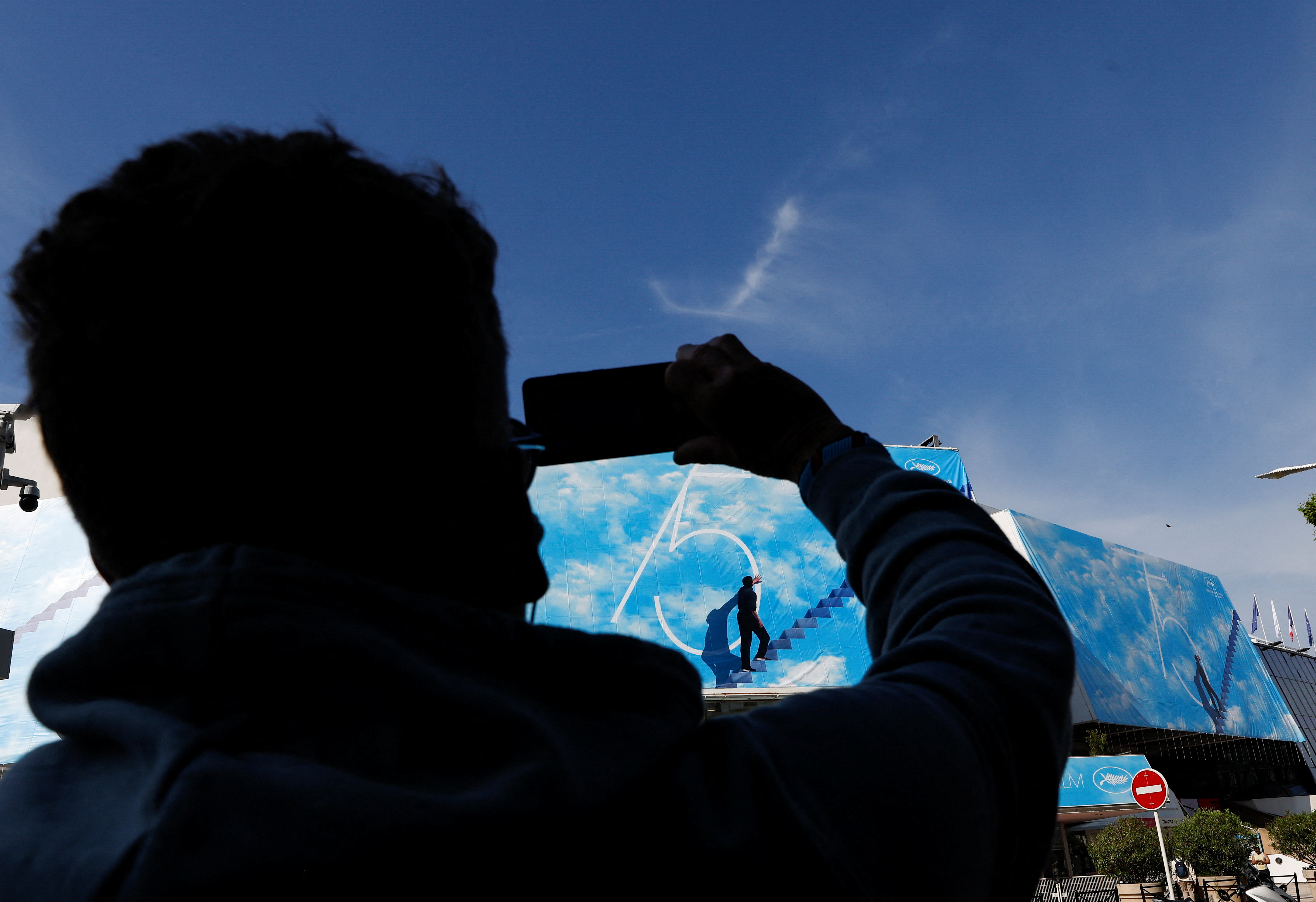 A man takes a photo of the official poster of the 75th Cannes Film Festival