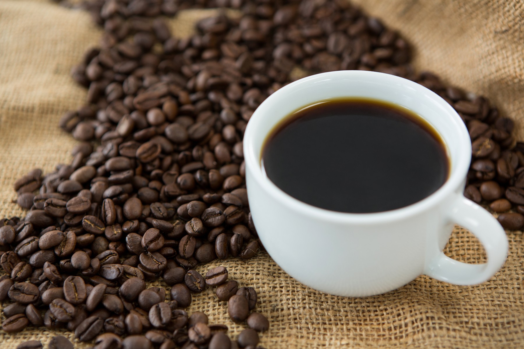 Cup of black coffee and roasted coffee beans