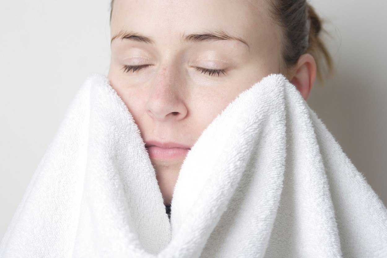 woman drying face with a white towel