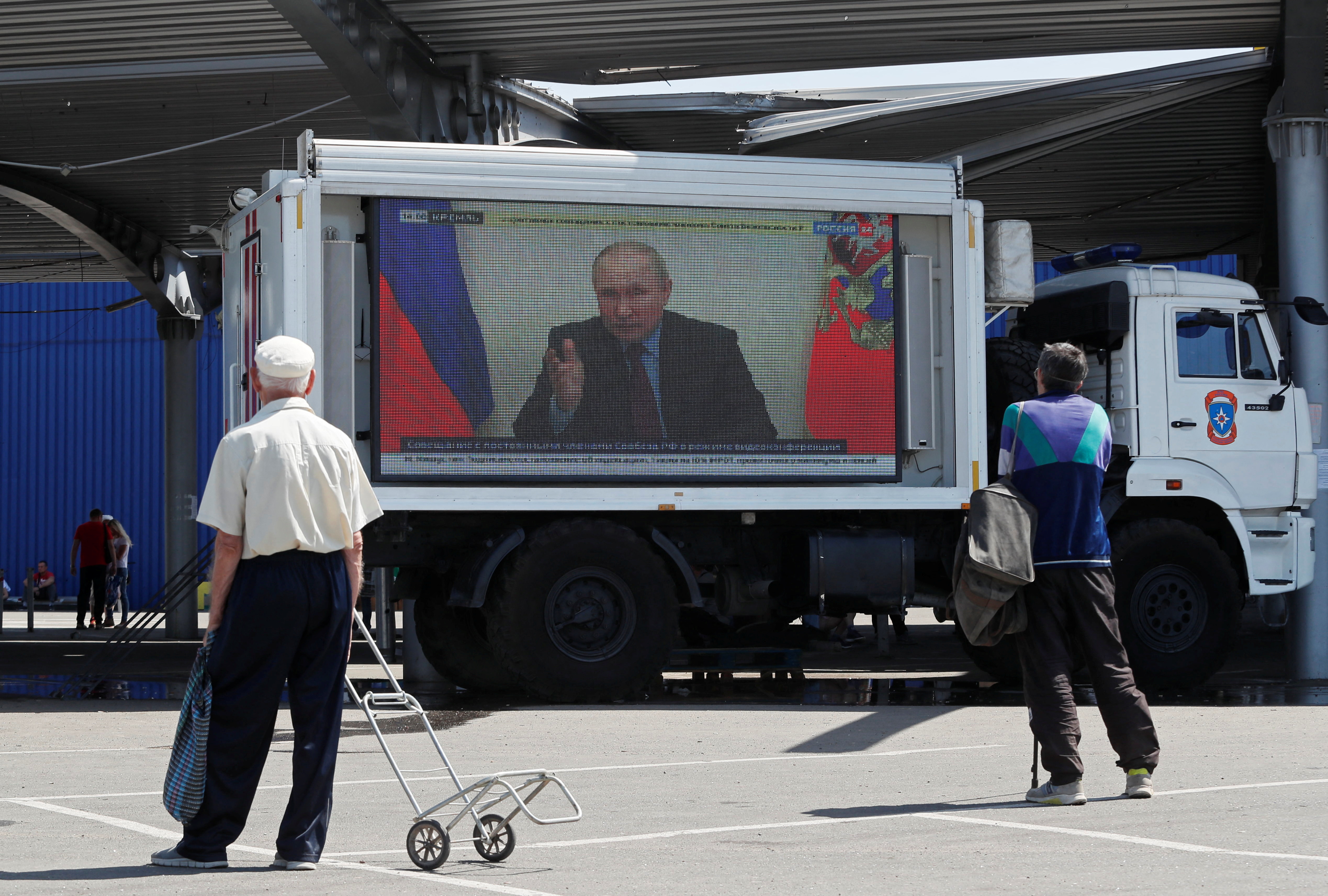 Russian President Vladimir Putin is seen on a screen broadcasting Russian TV news programs in Mariupol