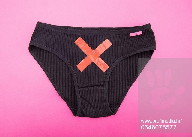 Black women's panties with a red cross on a pink background. Concept of female gynecological diseases, cervical erosion and polycystic ovary