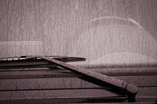 Color image of the wipers of a car, with rain drops on the windshield.