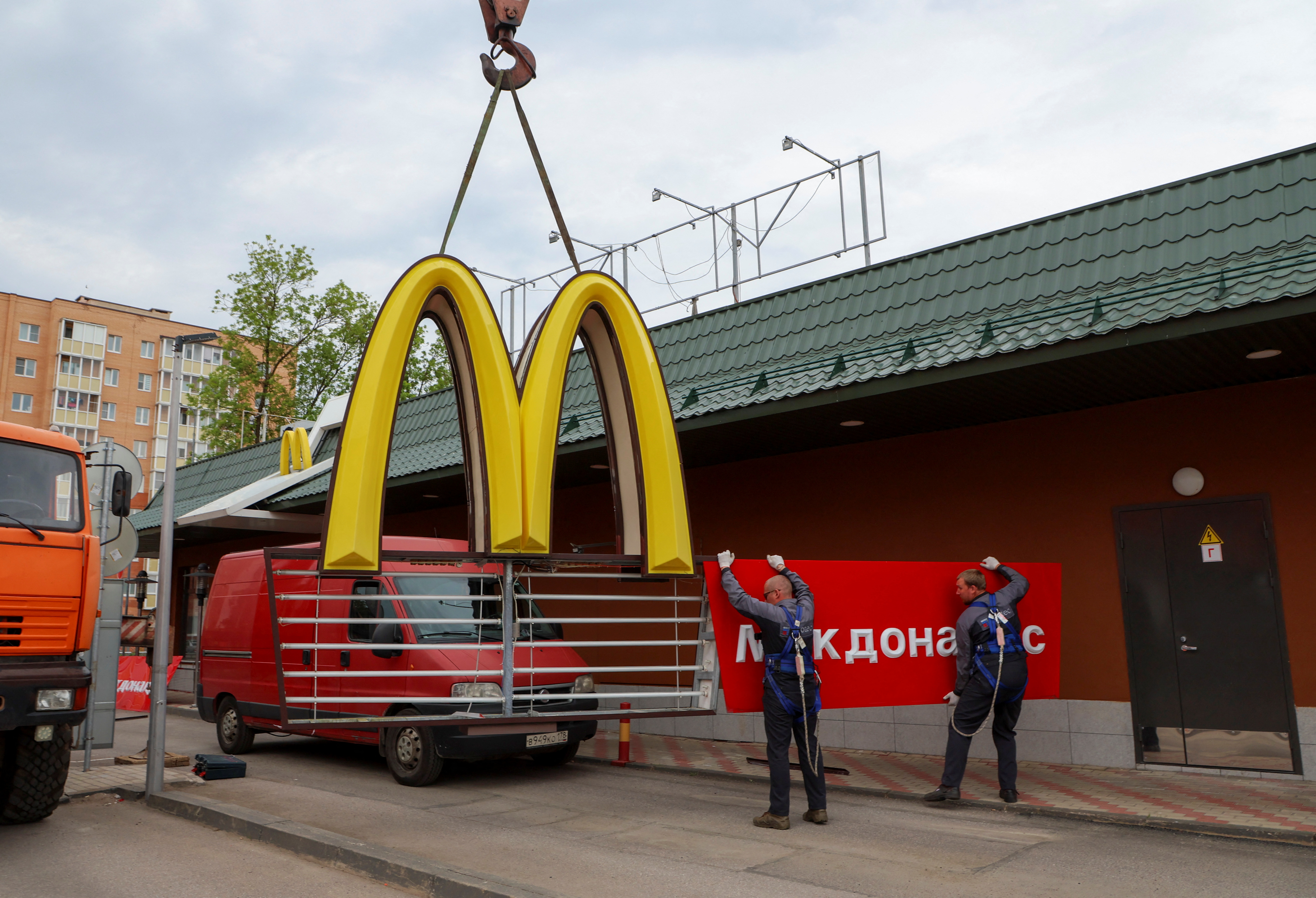 Workers remove the logo of McDonald's in Kingisepp
